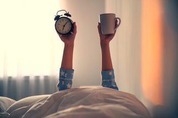 A woman holding up a mug and clock 