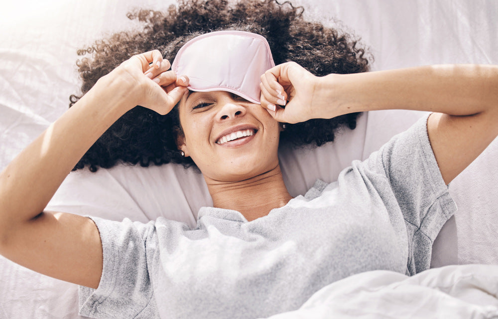 A woman looking under her sleep mask 