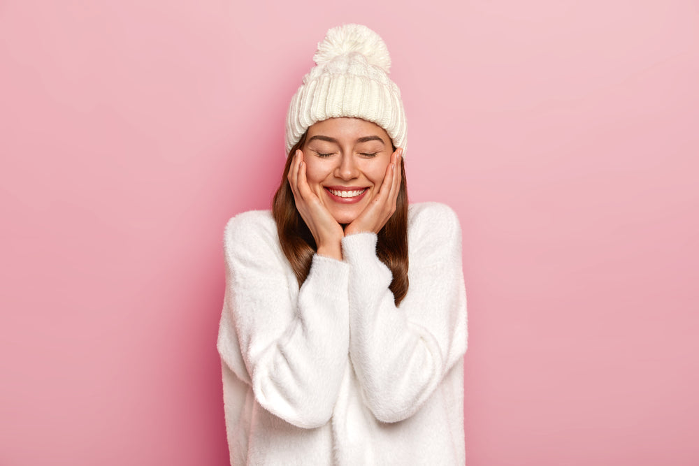 Woman wearing beanie hat holding cheeks
